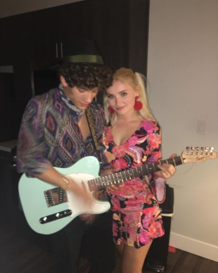 Eli Brown in a purple shirt holding guitar with Lauren Choulos in pink dress.